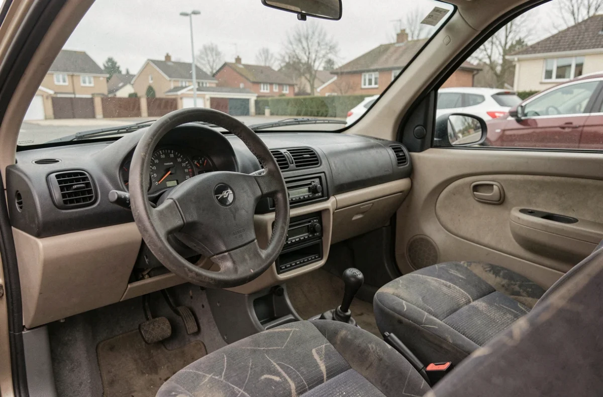 Intérieur sobre et usagé d'une voiture sans permis d'occasion avec tableau de bord minimaliste et siège tissu fatigué